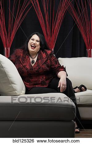 Stock Photograph - Caucasian woman laughing on sofa. Fotosearch