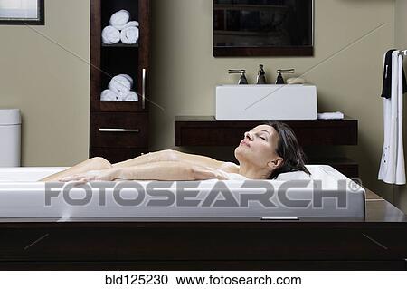 Stock Image - Caucasian woman relaxing in bubble bath. Fotosearch