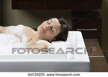Stock Image - Caucasian woman relaxing in bubble bath. Fotosearch