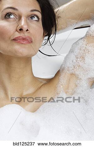 Stock Photo - Caucasian woman relaxing in bubble bath. Fotosearch