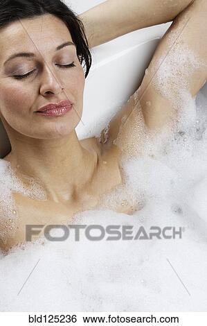 Stock Photograph - Caucasian woman relaxing in bubble bath. Fotosearch