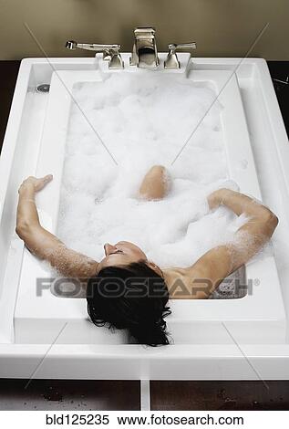 Stock Photography - Caucasian woman relaxing in bubble bath. Fotosearch