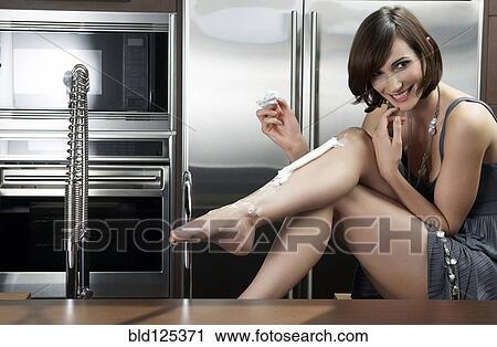 Caucasian woman shaving her legs in kitchen View Large Photo Image Stock Image - Caucasian woman shaving her legs in kitchen. Fotosearch