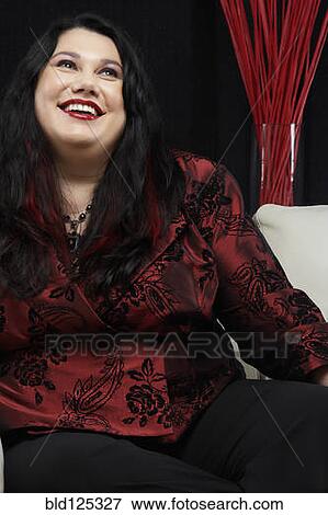 Stock Photo - Caucasian woman smiling on sofa. Fotosearch