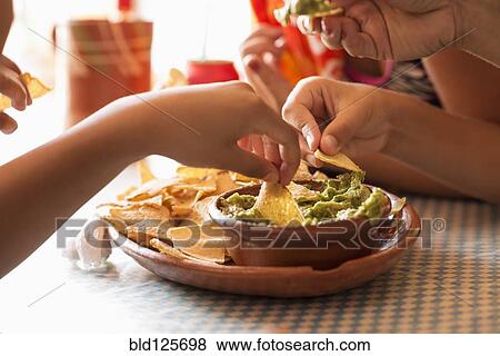 Stock Photo - Children eating chips and guacamole. Fotosearch