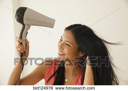Stock Photo - Chinese woman blow drying her hair. Fotosearch