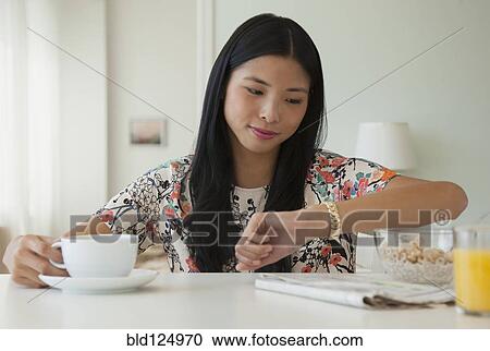 Chinese woman checking her watch at breakfast table View Large Photo Image Stock Image - Chinese woman checking her watch at breakfast table. Fotosearch