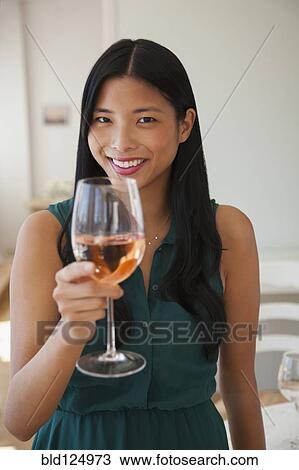 Stock Image - Chinese woman drinking glass of rose wine. Fotosearch