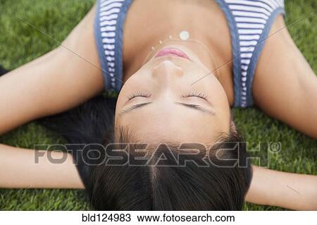 Stock Image - Chinese woman laying in grass. Fotosearch