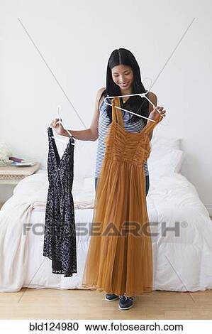 Chinese woman picking out dresses in bedroom View Large Photo Image Stock Image - Chinese woman picking out dresses in bedroom. Fotosearch