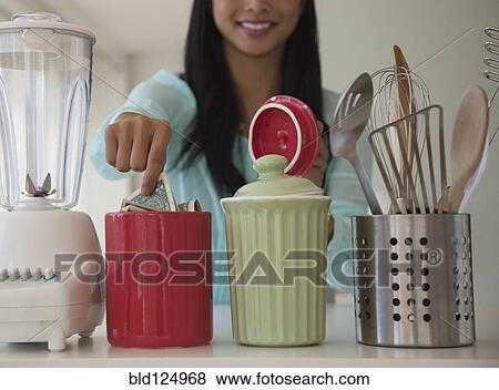 Stock Photo - Chinese woman putting money in savings jar. Fotosearch