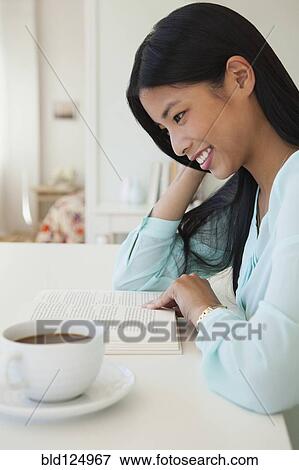 Stock Photo - Chinese woman reading with cup of coffee. Fotosearch