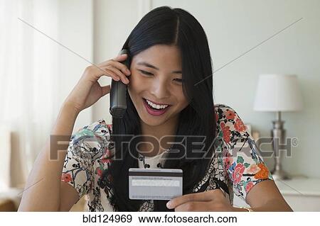 Stock Photo - Chinese woman shopping on telephone with credit card. Fotosearch