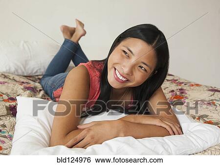Chinese woman smiling on bed View Large Photo Image Stock Photograph - Chinese woman smiling on bed. Fotosearch