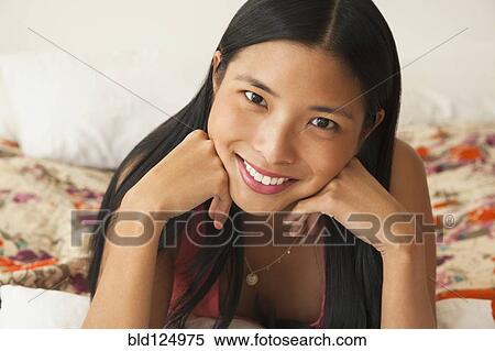 Stock Photography - Chinese woman smiling on bed. Fotosearch
