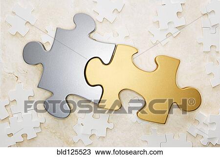 Stock Image - Close up of gold and silver puzzle pieces. Fotosearch