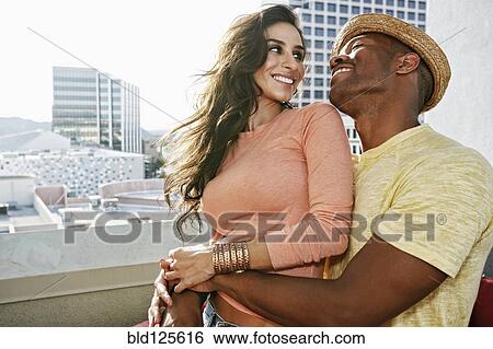 Couple hugging on urban balcony View Large Photo Image Stock Photograph - Couple hugging on urban balcony. Fotosearch