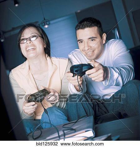 Stock Image - Couple playing video games together. Fotosearch