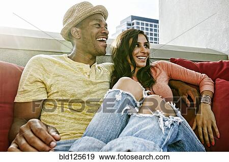 Couple relaxing on sofa on urban balcony View Large Photo Image Stock Photo - Couple relaxing on sofa on urban balcony. Fotosearch