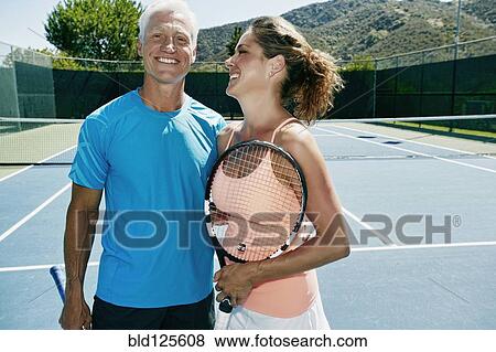 Couple smiling on tennis court View Large Photo Image Stock Photo - Couple smiling on tennis court. Fotosearch