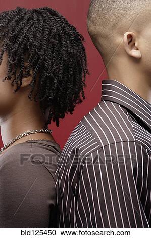 Stock Image - Couple standing back to back. Fotosearch