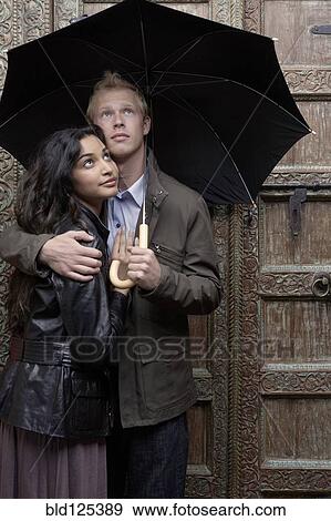 Couple under umbrella at ornate door View Large Photo Image Stock Photo - Couple under umbrella at ornate door. Fotosearch