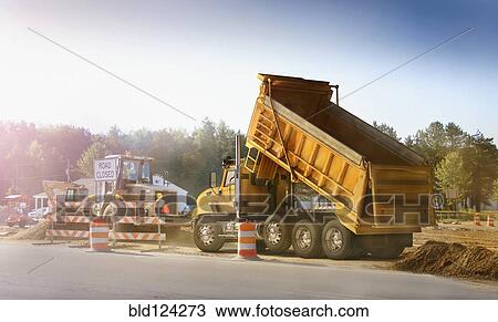 Stock Image - Dump truck dumping haul on site. Fotosearch