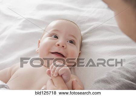 Father admiring Hispanic baby boy on bed View Large Photo Image Stock Photo - Father admiring Hispanic baby boy on bed. Fotosearch
