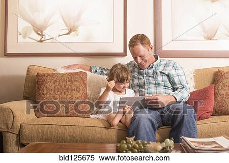 Father and daughter using digital tablet on sofa View Large Photo Image Stock Photography - Father and daughter using digital tablet on sofa. Fotosearch
