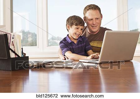 Father and son using laptop at desk View Large Photo Image Stock Image - Father and son using laptop at desk. Fotosearch