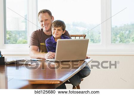Stock Image - Father and son using laptop together. Fotosearch