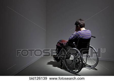Stock Photo - Frustrated Caucasian man in wheelchair in corner. Fotosearch