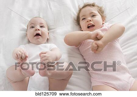 Hispanic babies laying on bed View Large Photo Image Stock Photo - Hispanic babies laying on bed. Fotosearch