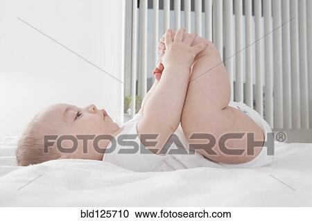 Stock Image - Hispanic baby boy playing with feet. Fotosearch