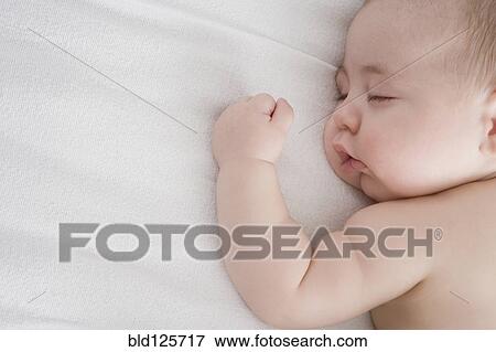 Stock Photo - Hispanic baby boy sleeping on bed. Fotosearch