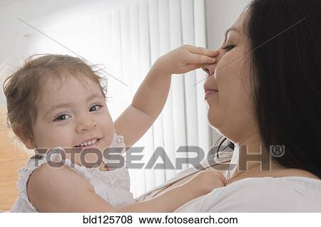 Stock Photo - Hispanic baby girl touching mother's nose. Fotosearch