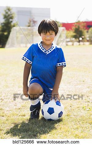 Hispanic boy with soccer ball kneeling on field View Large Photo Image Stock Photograph - Hispanic boy with soccer ball kneeling on field. Fotosearch