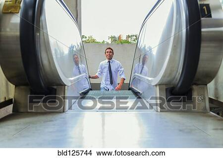 Picture - Hispanic businessman riding escalator. Fotosearch