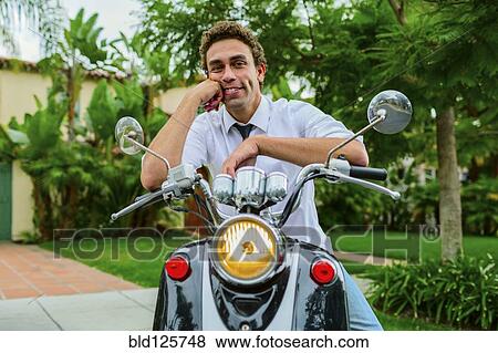 Hispanic businessman sitting on moped outdoors View Large Photo Image Stock Photo - Hispanic businessman sitting on moped outdoors. Fotosearch