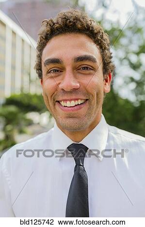 Stock Image - Hispanic businessman smiling outdoors. Fotosearch