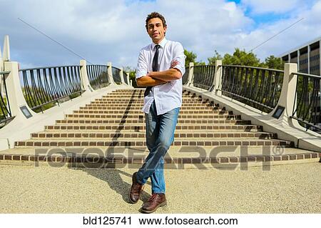Stock Image - Hispanic businessman standing by urban steps. Fotosearch