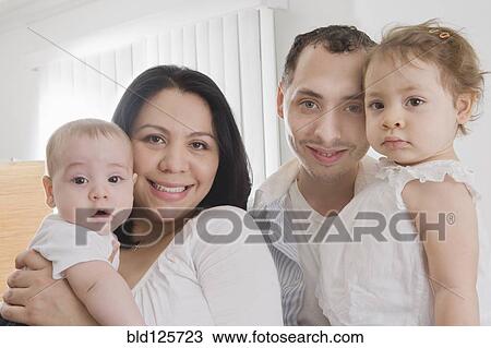 Stock Image - Hispanic family smiling together indoors. Fotosearch