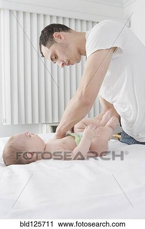 Hispanic father changing baby boy's diaper View Large Photo Image Stock Image - Hispanic father changing baby boy's diaper. Fotosearch