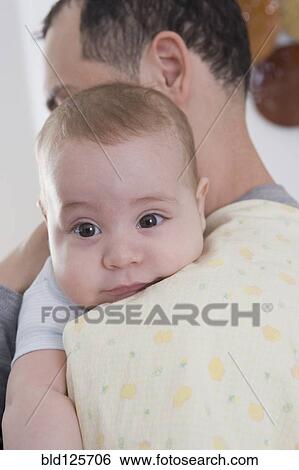 Stock Photograph - Hispanic father holding baby boy on his shoulder. Fotosearch