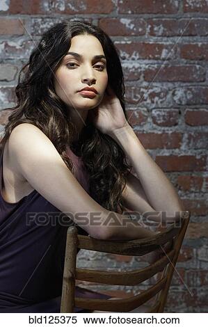 Stock Photography - Hispanic woman sitting in wooden chair. Fotosearch