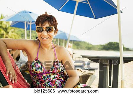 Hispanic woman smiling in lounge chair View Large Photo Image Stock Photograph - Hispanic woman smiling in lounge chair. Fotosearch