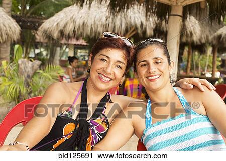 Stock Image - Hispanic women smiling at resort. Fotosearch