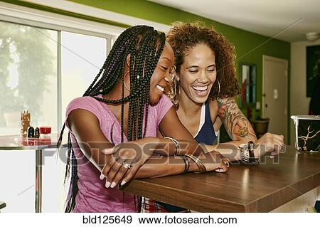 Homosexual couple laughing together in kitchen View Large Photo Image Stock Photo - Homosexual couple laughing together in kitchen. Fotosearch