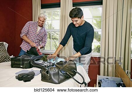 Picture - Homosexual couple packing suitcases in bedroom. Fotosearch