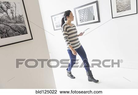 Stock Image - Korean woman admiring art in gallery. Fotosearch